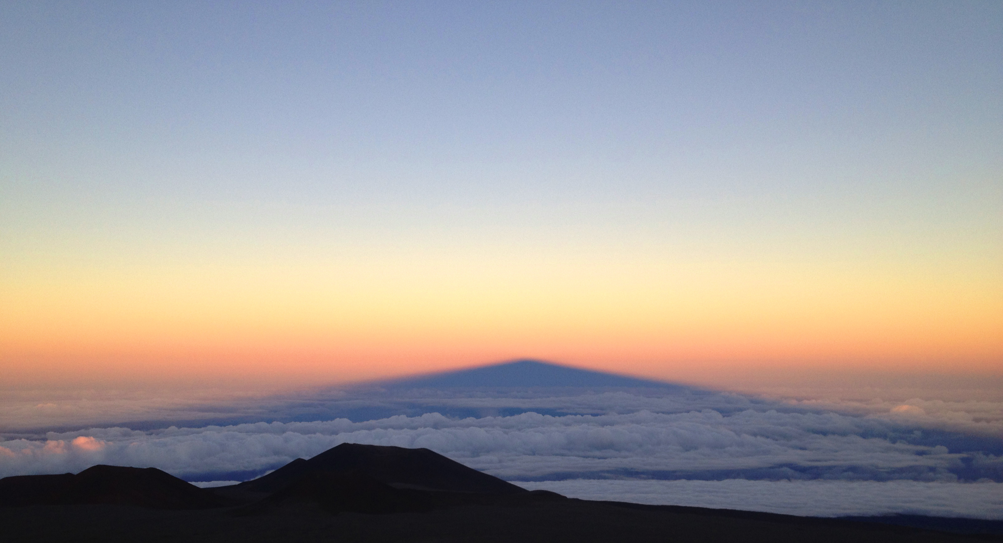 The shadow of Mauna Kea peak on the clouds down below
